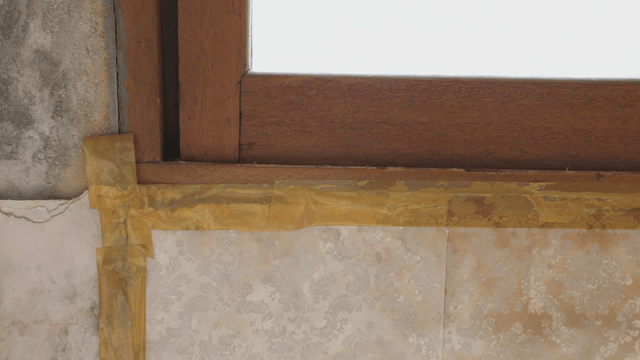 Window with yellow tape on the wall