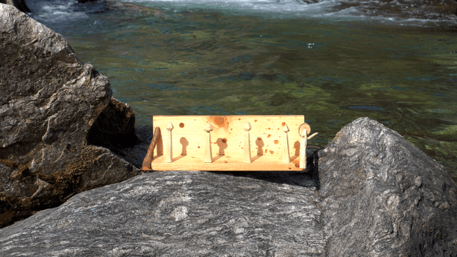 Wooden shelf placed on a rock by the clear stream