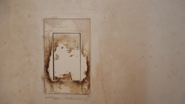 Aged light switch on a stained wall