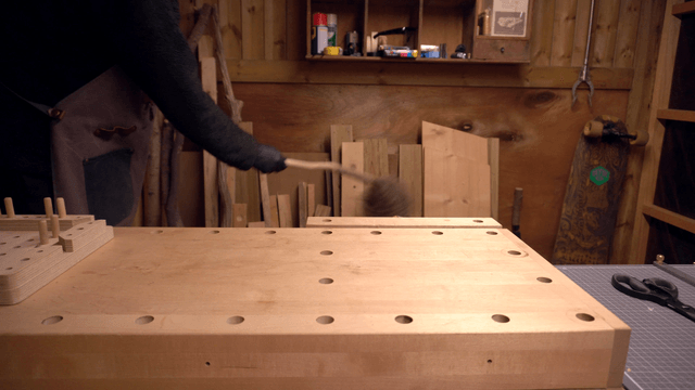 Person cleaning a wooden workbench