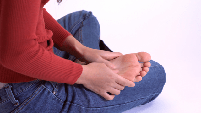 Person sitting cross-legged massaging foot
