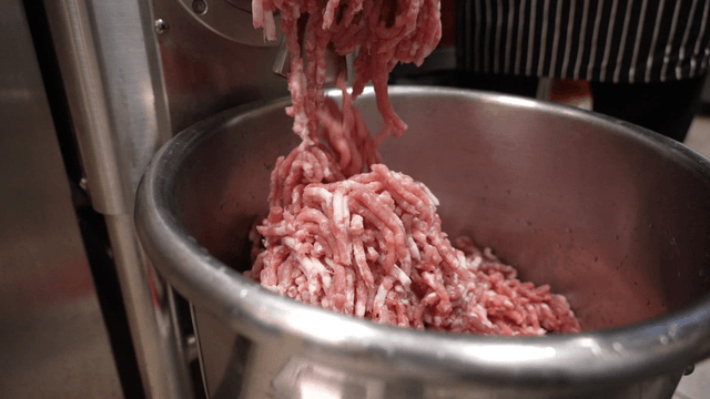 Meat being ground in processing machine