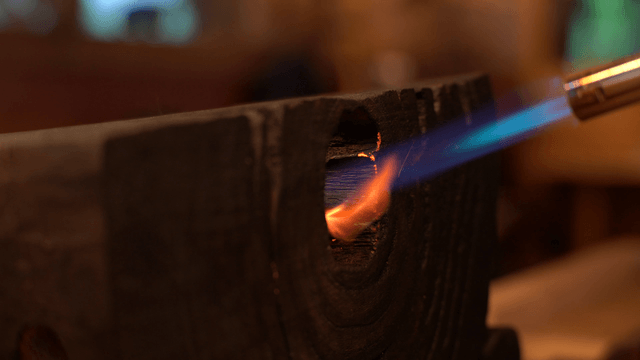 Blowtorch burning holes into wooden sculpture