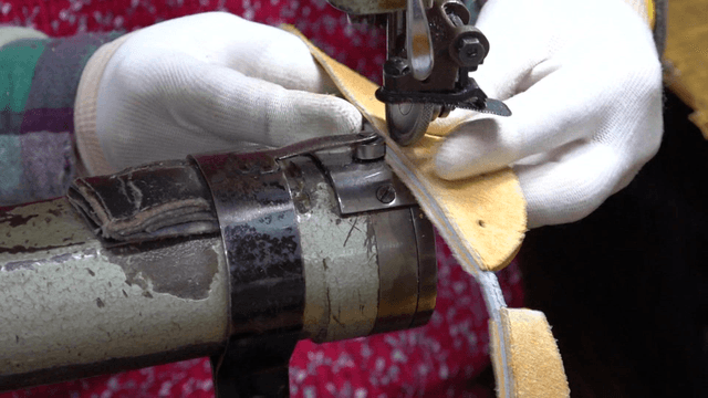 Worker sewing leather with industrial sewing machine