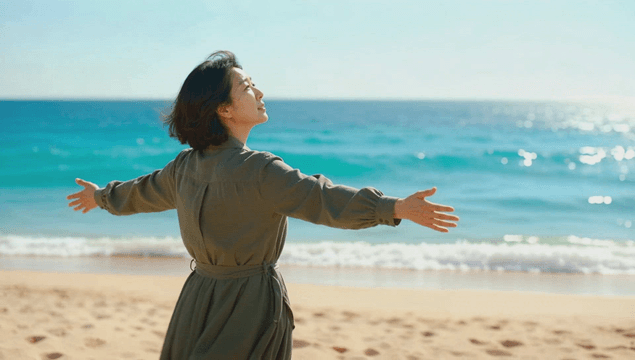 Woman standing with open arms in a windy sea