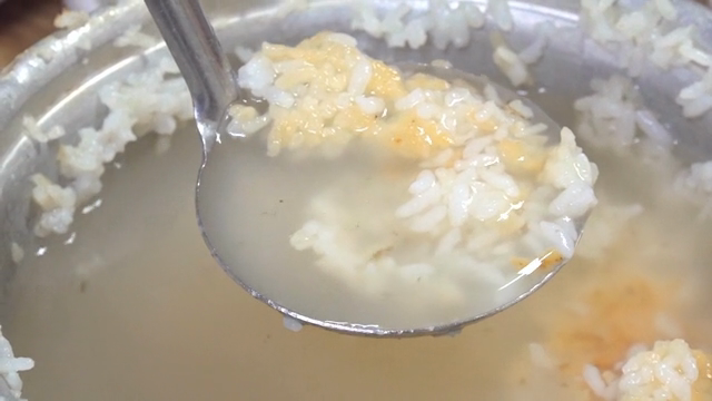 Scooping up scorched rice from the pot with a ladle