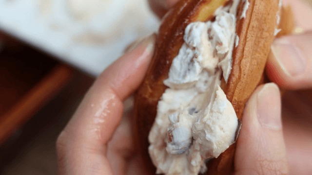 Hands holding a cream-filled bread