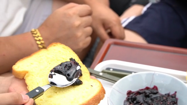 Spreading berry jam on bread slices