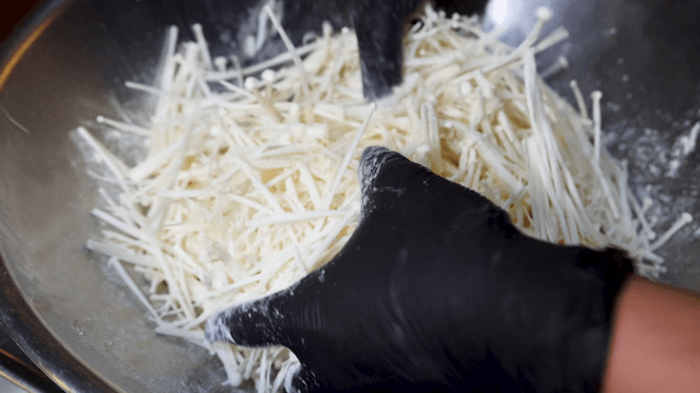 Mixing flour with enoki mushrooms in bowl