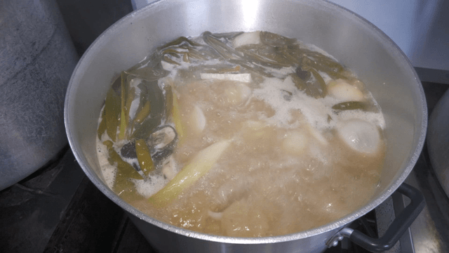 Rich meat broth with vegetables boiling in a pot