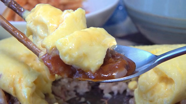 A spoonful of omelet rice with rich sauce