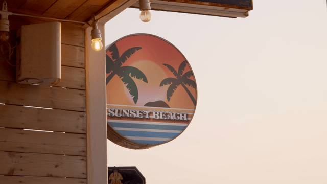 Sign with palm trees at sunset