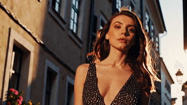 A woman standing down a sunlit street