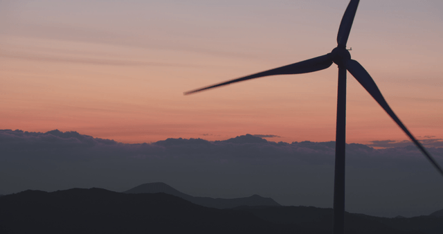 Wind turbine at sunset with mountains