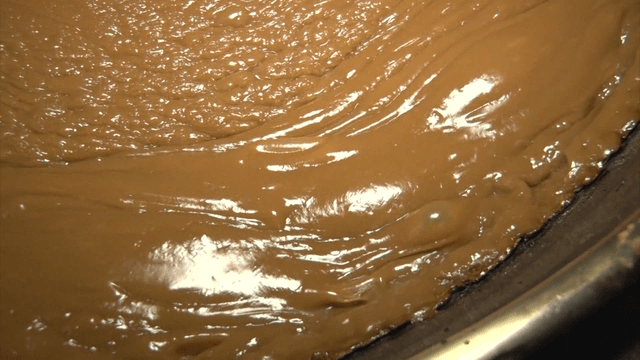 Thick brown sauce bubbling in a pot
