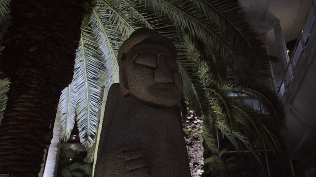 Stone statue under palm trees at night