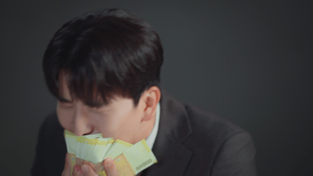 Man in a suit smelling a stack of money