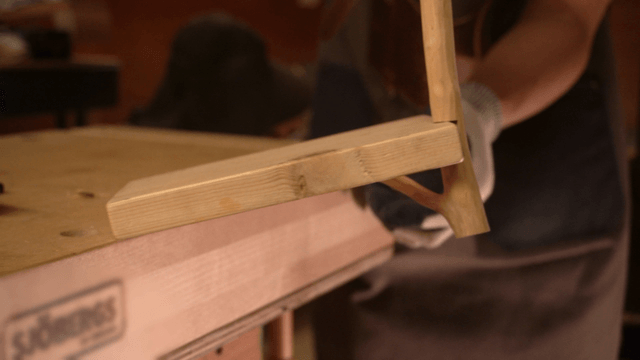 Woodcraft artisan inspecting assembled wooden pieces in workshop