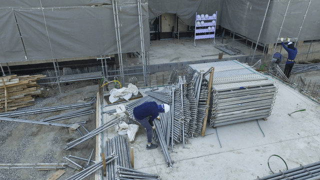 Construction workers organizing metal pipes