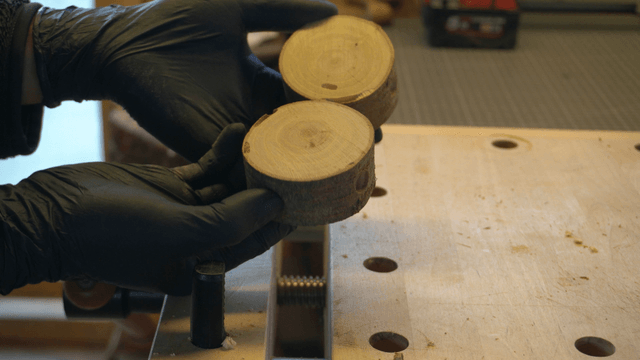 Hand inspecting a holed wooden piece on workbench