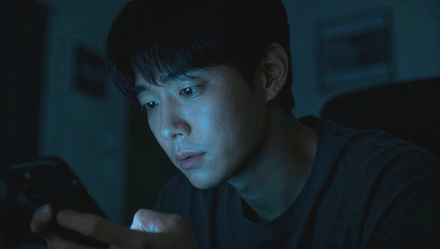 Man focused on using a smartphone in a dark room