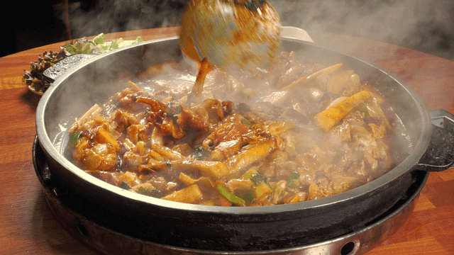 Stir-fried chicken cooking in a sizzling pan