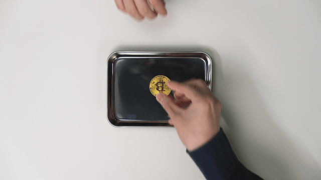 Hand receiving a tray with Bitcoin on it