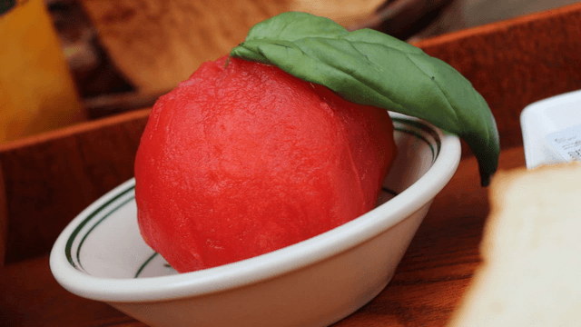 A fresh tomato marinated with basil on a plate