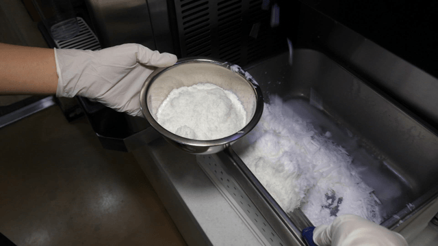 Scooping ice into a metal bowl