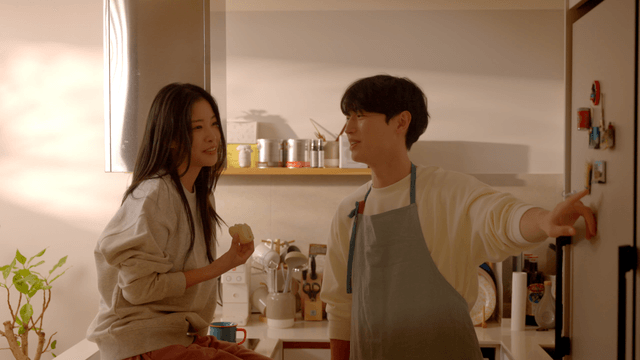 Happy couple talking while looking at refrigerator in kitchen