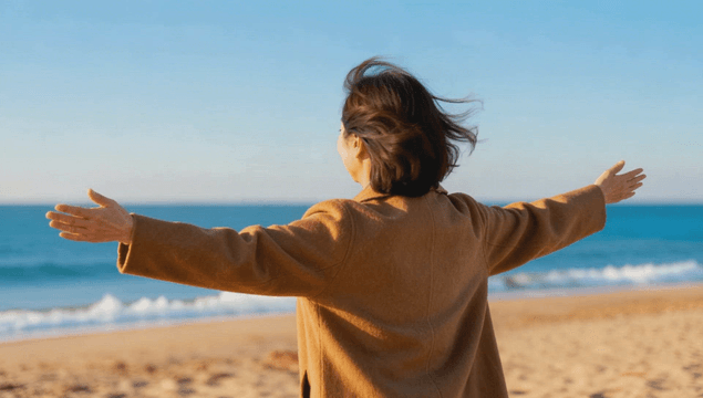 Woman enjoying with arms open at the sea