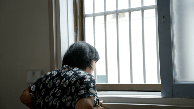 Back view of an elderly woman looking out the window
