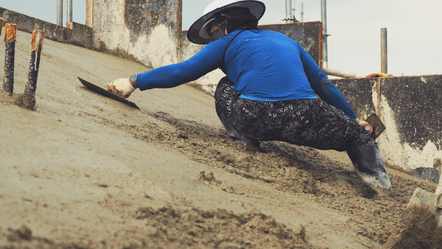 Worker smoothing concrete on a slope