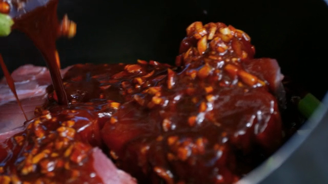 Pouring sauce over raw meat in a pan