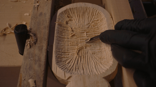 Hands crafting a wooden piece with fine patterns
