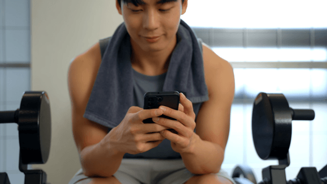 Man using smartphone in a gym setting