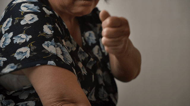 An elderly woman massaging her arm