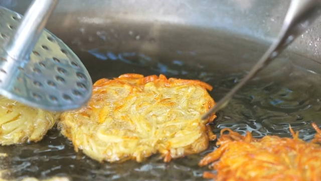 Golden potato pancakes frying in a pan
