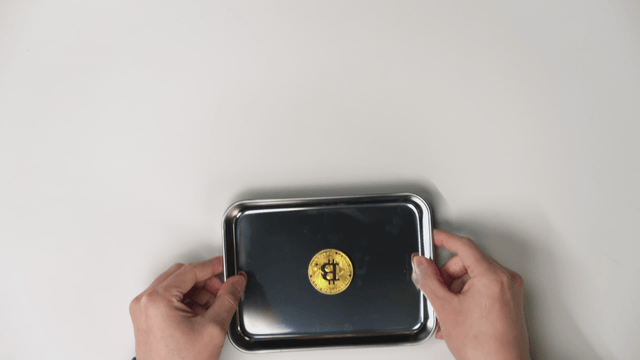 Hand taking a tray with a Bitcoin on it