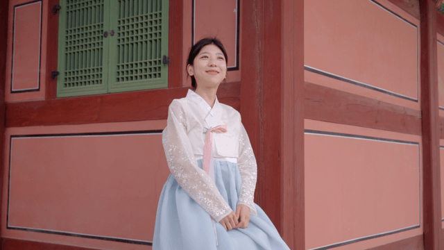 한복을 입고 전통 장소에서 미소 짓는 여성
