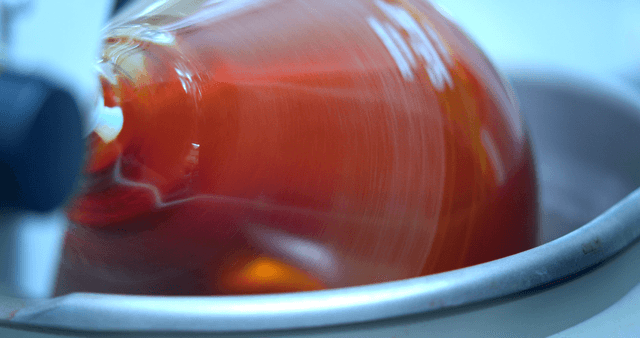 Swirling red liquid inside a laboratory glass vessel
