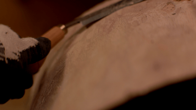 Artisan shaping wood surface with a drawknife