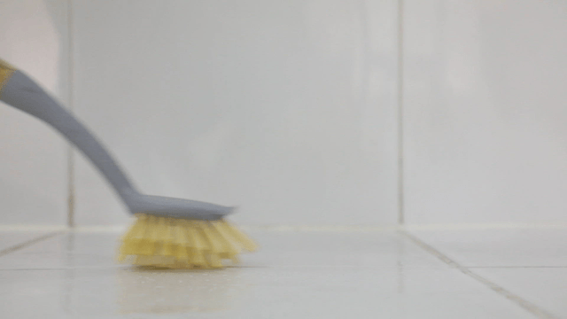 Cleaning a tiled floor with a brush