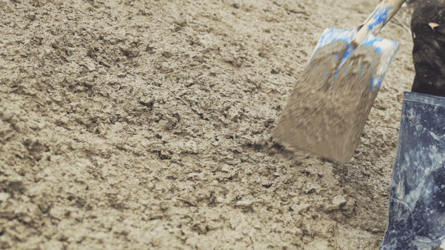 Person mixing concrete with a shovel