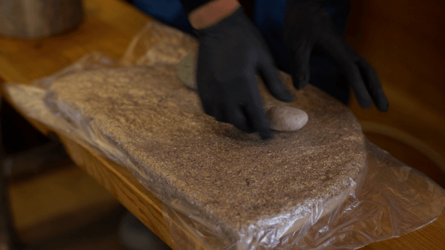 Woodcraft artisan pressing wood and sawdust with stone to shape form