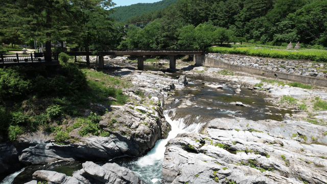 Clear valley stream flowing between rocks under bridge