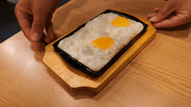 Fried egg sizzling on a hot iron plate