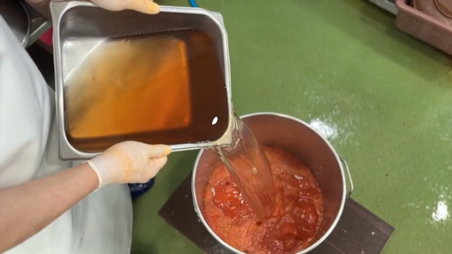 Pouring liquid into a pot of red mixture