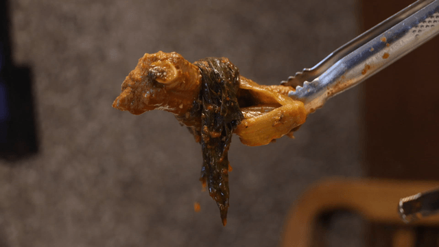 Spicy gatgimchi pork back-rib stew lifted with tongs