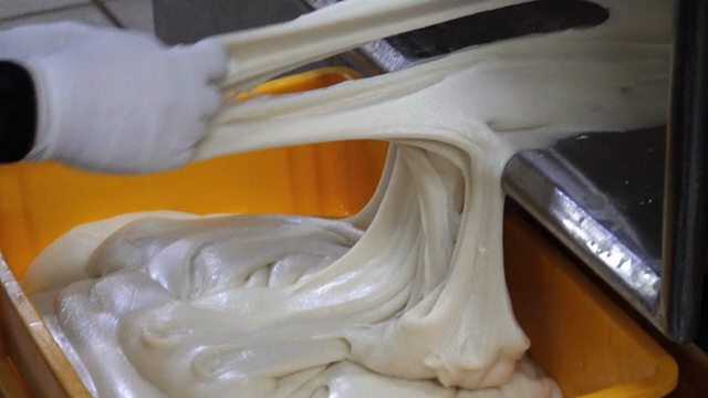 A worker taking out rice cake dough from a machine